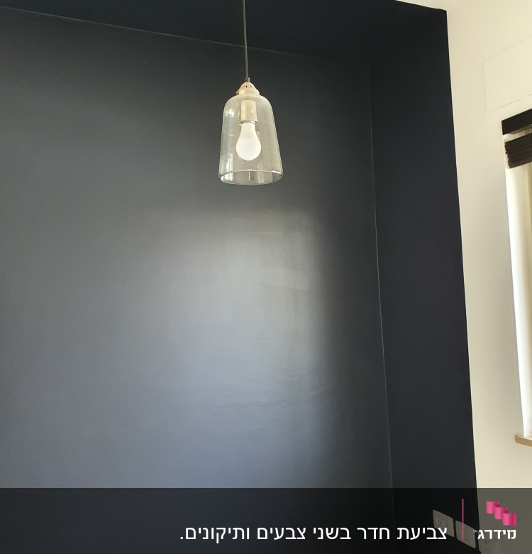 קיר צבוע בכחול כהה עם מנורה תלויה